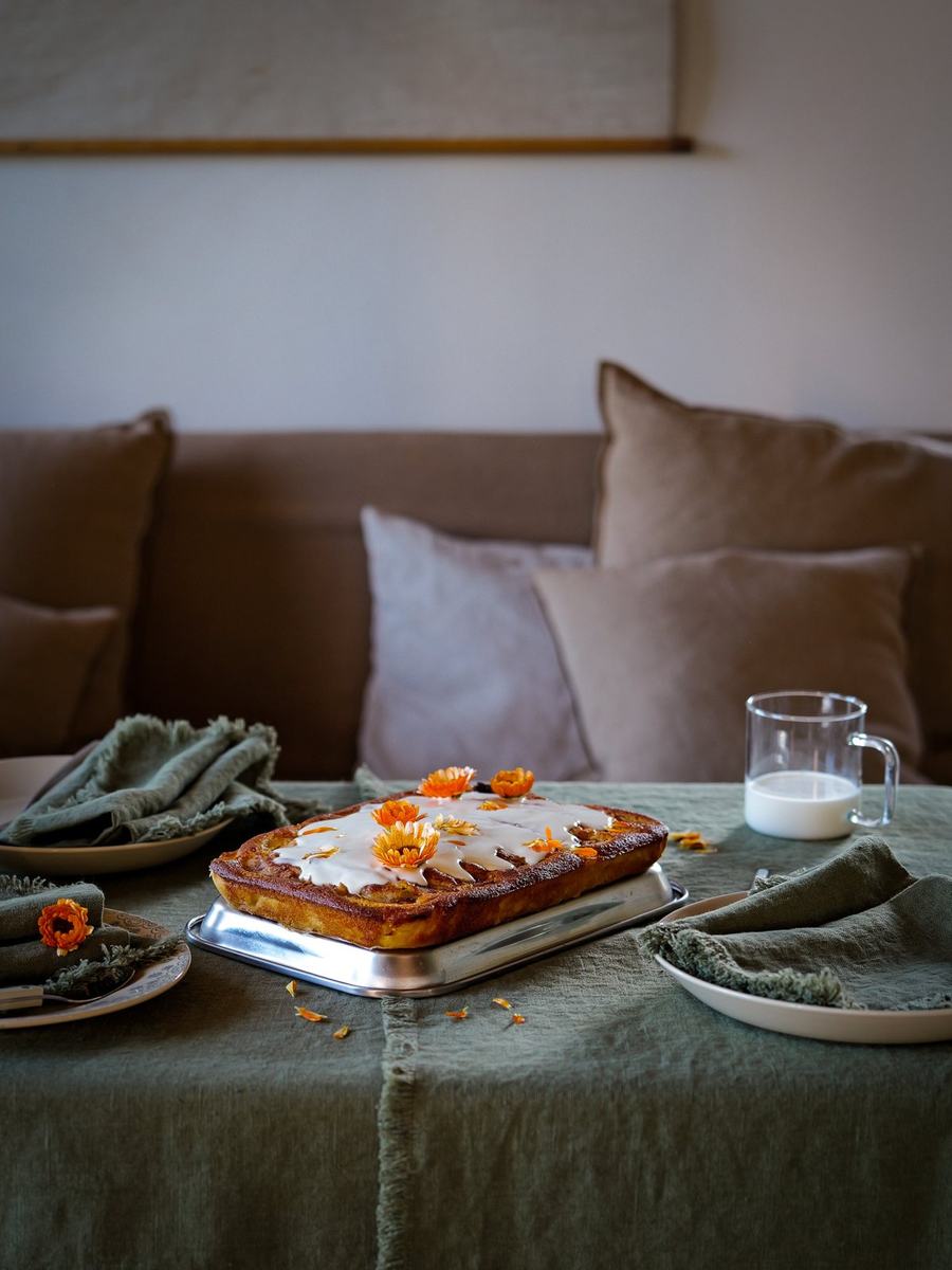 Gâteau aux fleurs orange sur du lin vert olive et des serviettes à franges