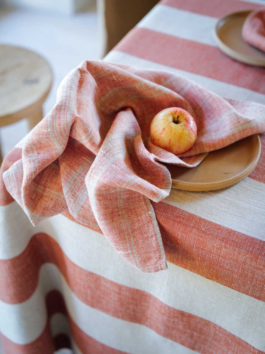 Serviette en lin rayée brique avec une pomme sur une assiette beige