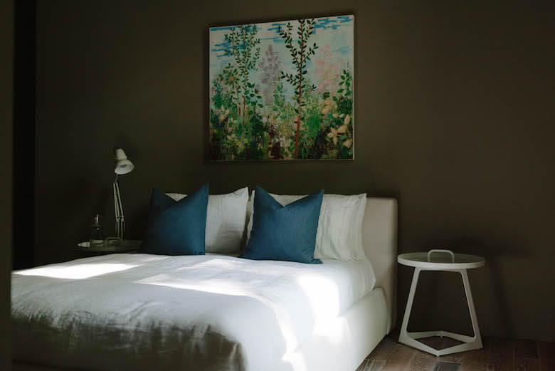 Chambre moderne sombre avec linge de lit blanc en lin et coussins bleus