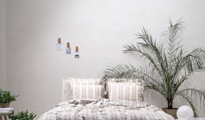 Chambre d’amis avec du linge de lit en lin rayé et des plantes