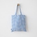 Sac cabas en lin à carreaux vichy bleus suspendu de face à un crochet mural
